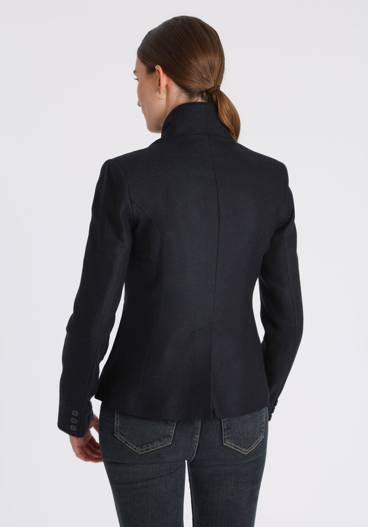 Model wearing the Tallulah jacket in navy herringbone lambswool with suede trim, a tailored style with a single button fastening and a collar that can be worn turned up or down.