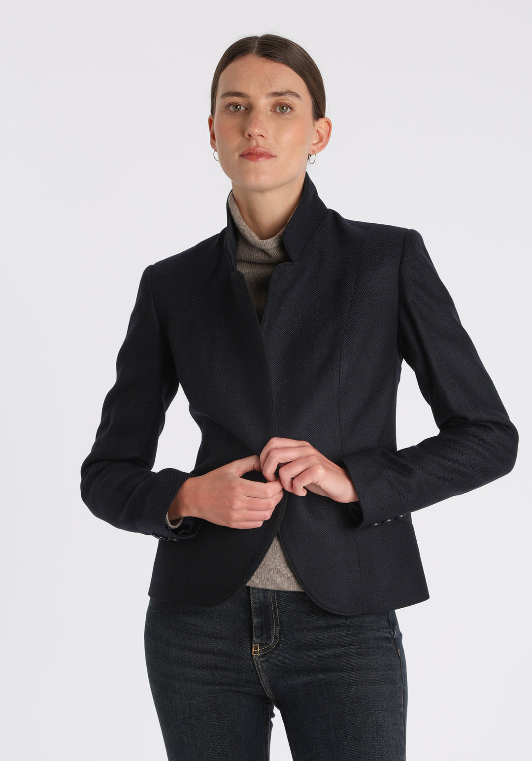 Model wearing the Tallulah jacket in navy herringbone lambswool with suede trim, a tailored style with a single button fastening and a collar that can be worn turned up or down.