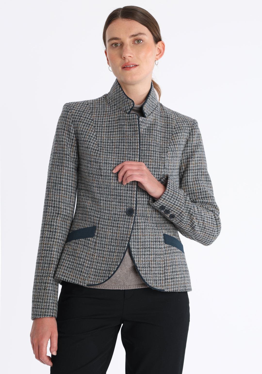 Model wearing the Tallulah jacket in grey and ochre dogtooth check with suede trim, a tailored style with a single button fastening and a collar that can be worn turned up or down.