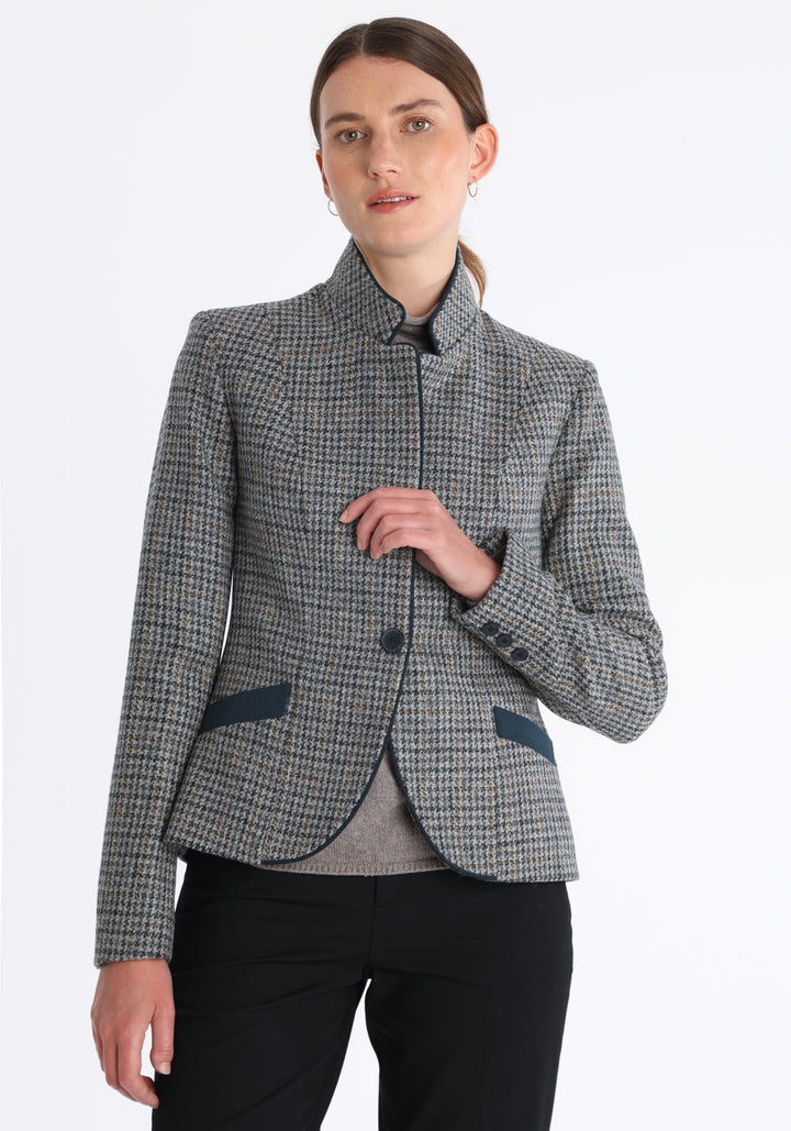 Model wearing the Tallulah jacket in grey and ochre dogtooth check with suede trim, a tailored style with a single button fastening and a collar that can be worn turned up or down.