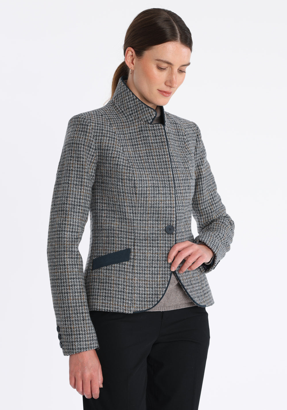 Model wearing the Tallulah jacket in grey and ochre dogtooth check with suede trim, a tailored style with a single button fastening and a collar that can be worn turned up or down.
