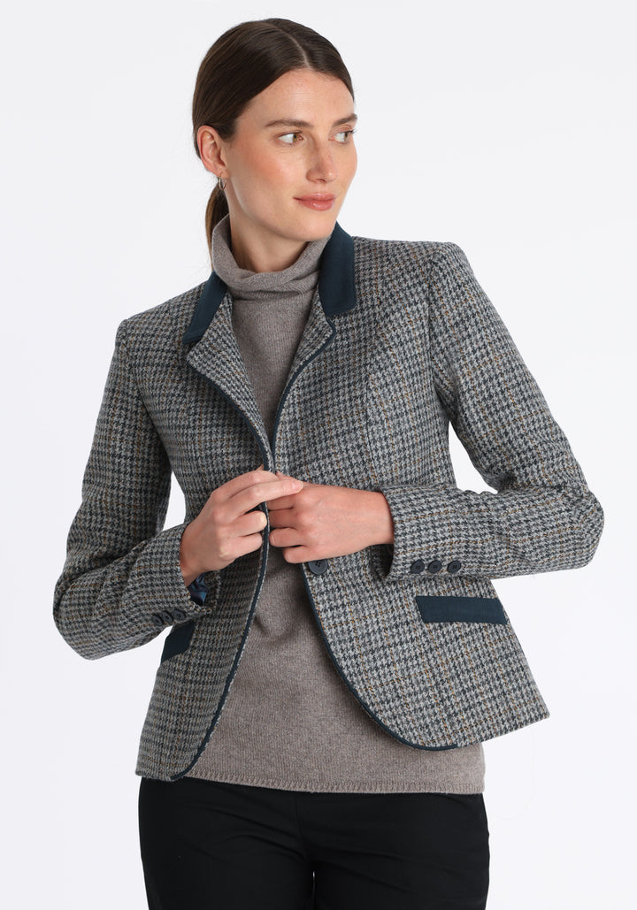 Model wearing the Tallulah jacket in grey and ochre dogtooth check with suede trim, a tailored style with a single button fastening and a collar that can be worn turned up or down.