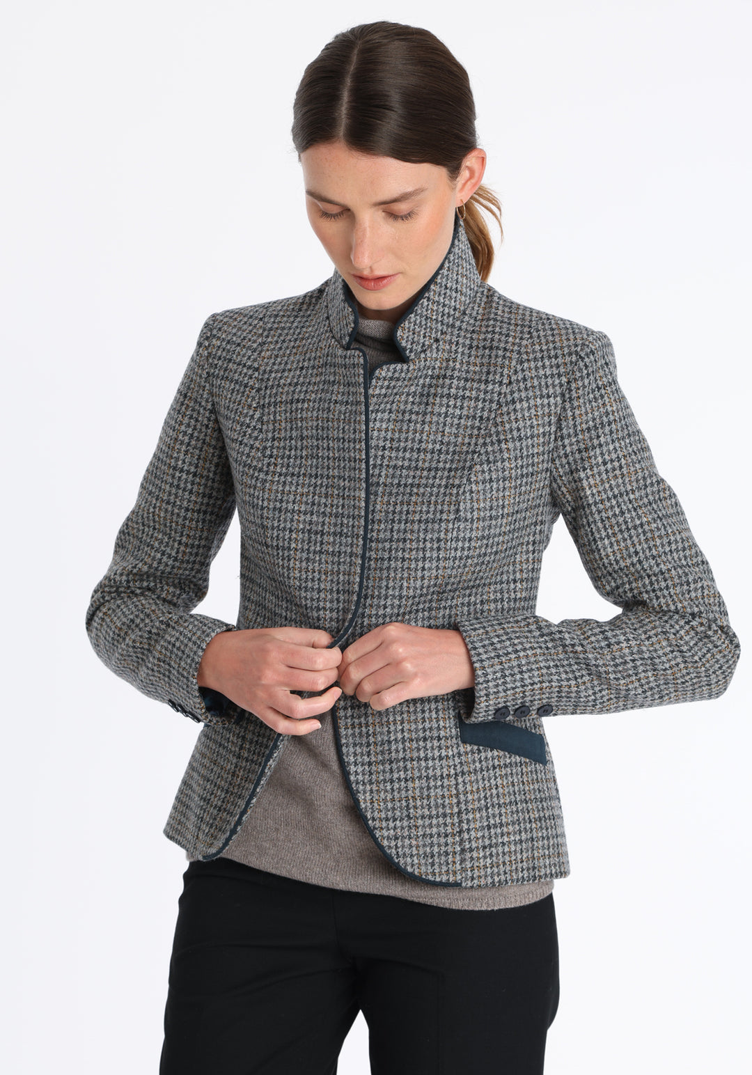 Model wearing the Tallulah jacket in grey and ochre dogtooth check with suede trim, a tailored style with a single button fastening and a collar that can be worn turned up or down.