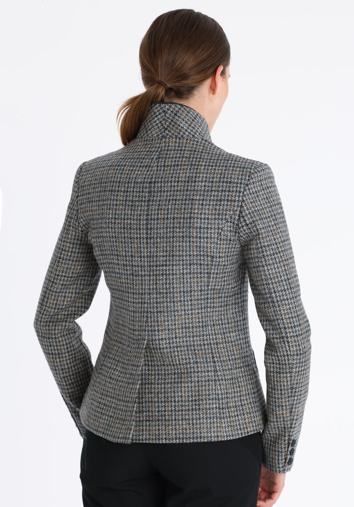 Model wearing the Tallulah jacket in grey and ochre dogtooth check with suede trim, a tailored style with a single button fastening and a collar that can be worn turned up or down.