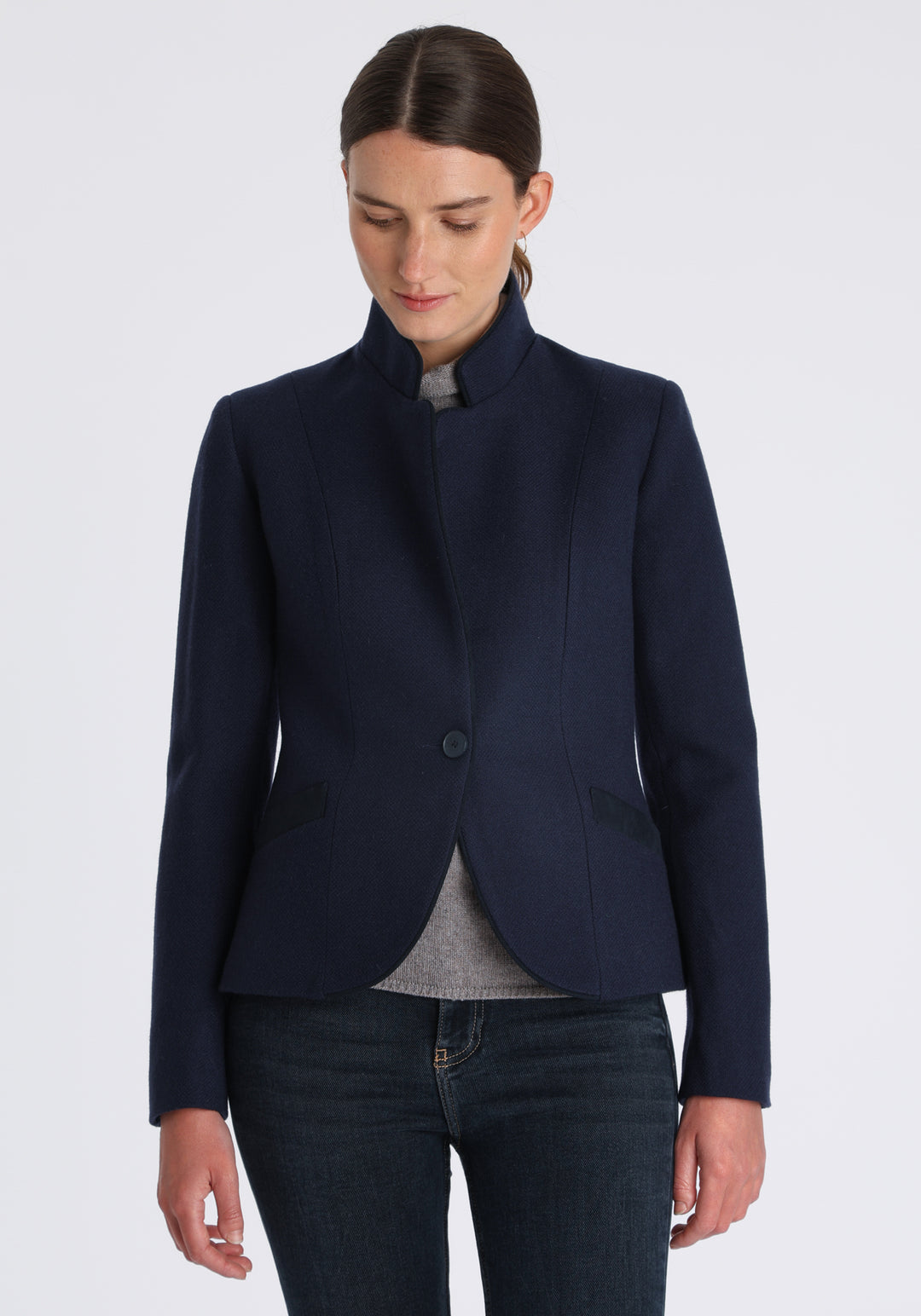 Model wearing the Tallulah jacket in navy textured merino wool with suede trim, a tailored style with a single button fastening and a collar that can be worn turned up or down.