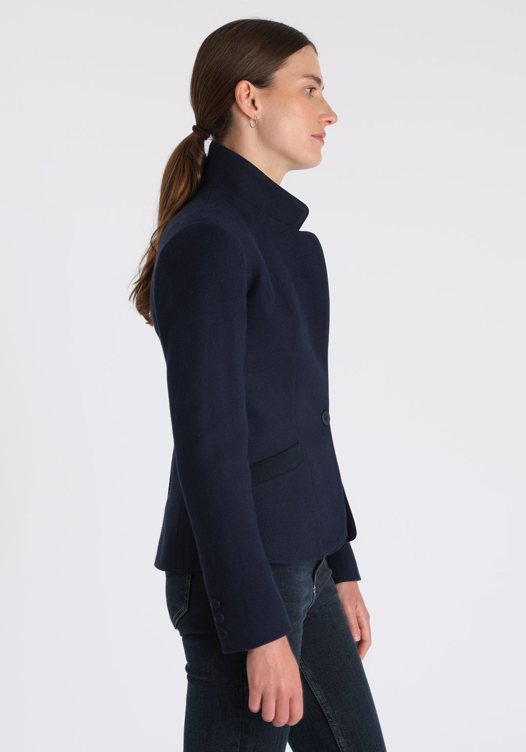 Model wearing the Tallulah jacket in navy textured merino wool with suede trim, a tailored style with a single button fastening and a collar that can be worn turned up or down.
