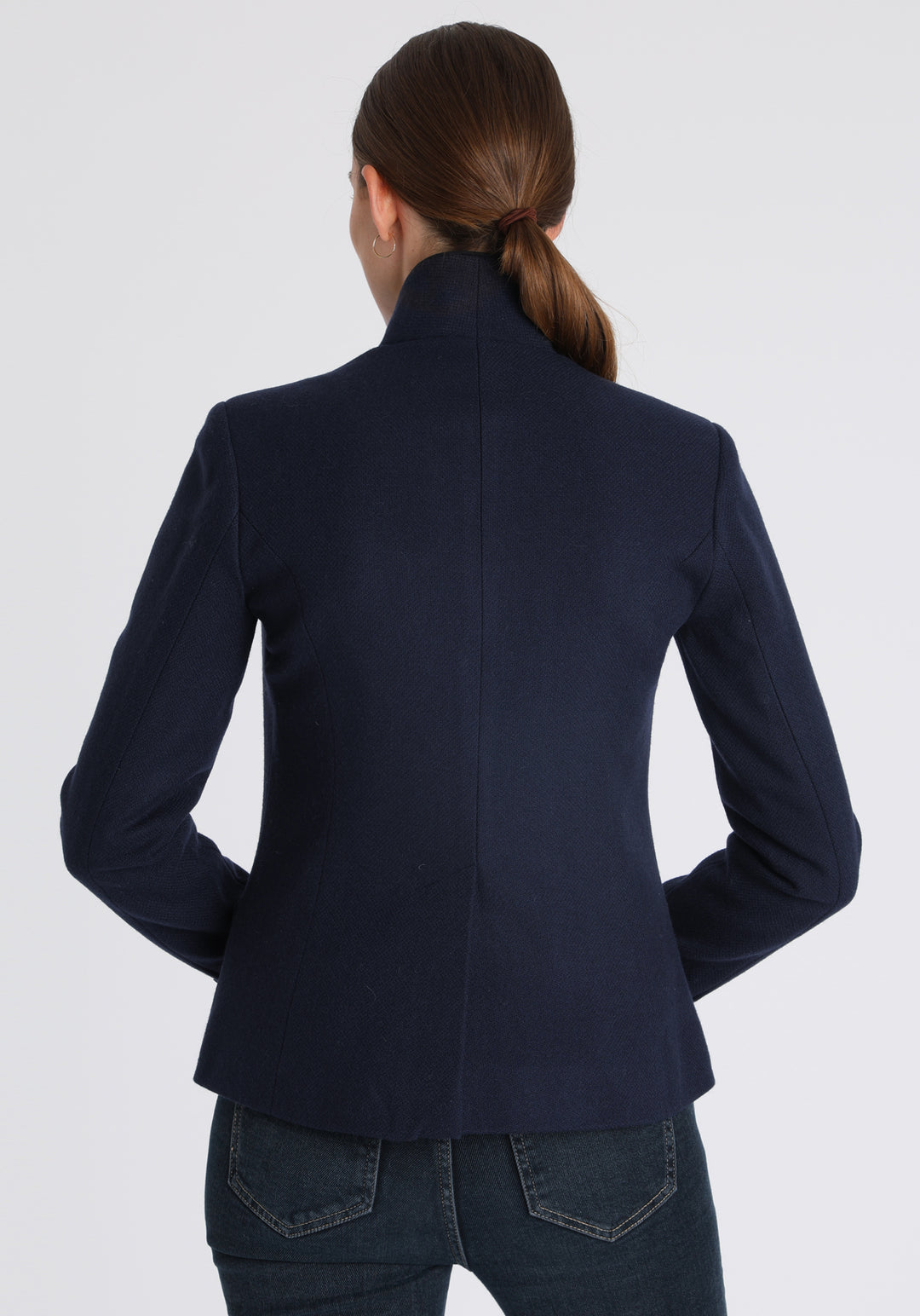 Model wearing the Tallulah jacket in navy textured merino wool with suede trim, a tailored style with a single button fastening and a collar that can be worn turned up or down.