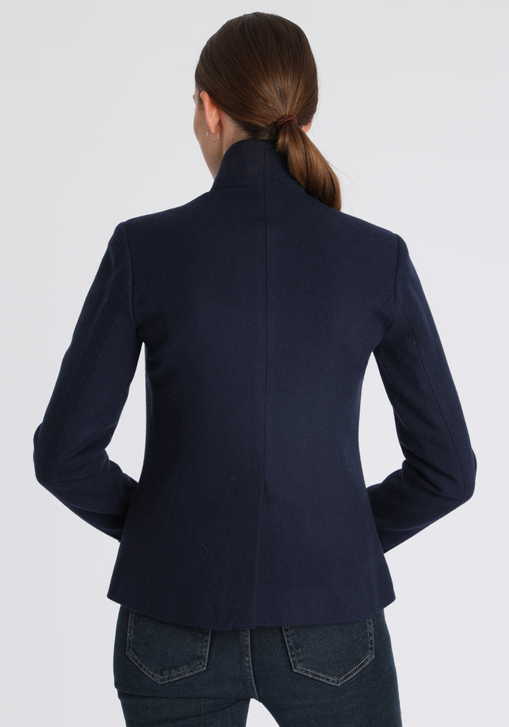 Model wearing the Tallulah jacket in navy textured merino wool with suede trim, a tailored style with a single button fastening and a collar that can be worn turned up or down.