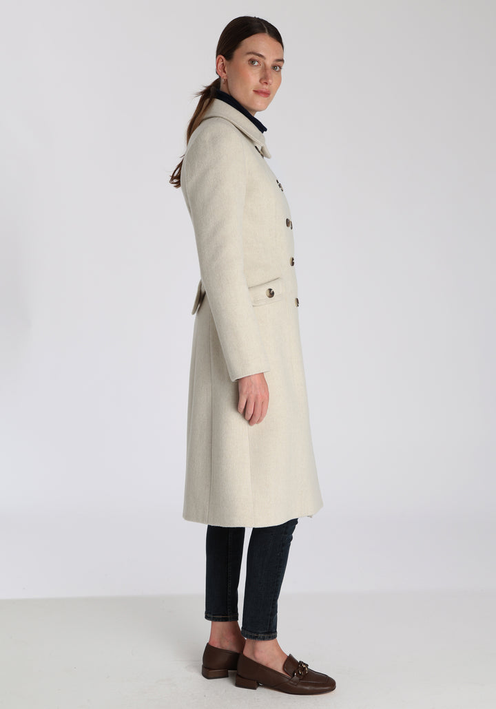 Model wearing the Tori coat in cream merino wool, a vintage-inspired style with a double-breasted front, gently flared skirt, and curved detailing on the collar, pockets, and back belt.