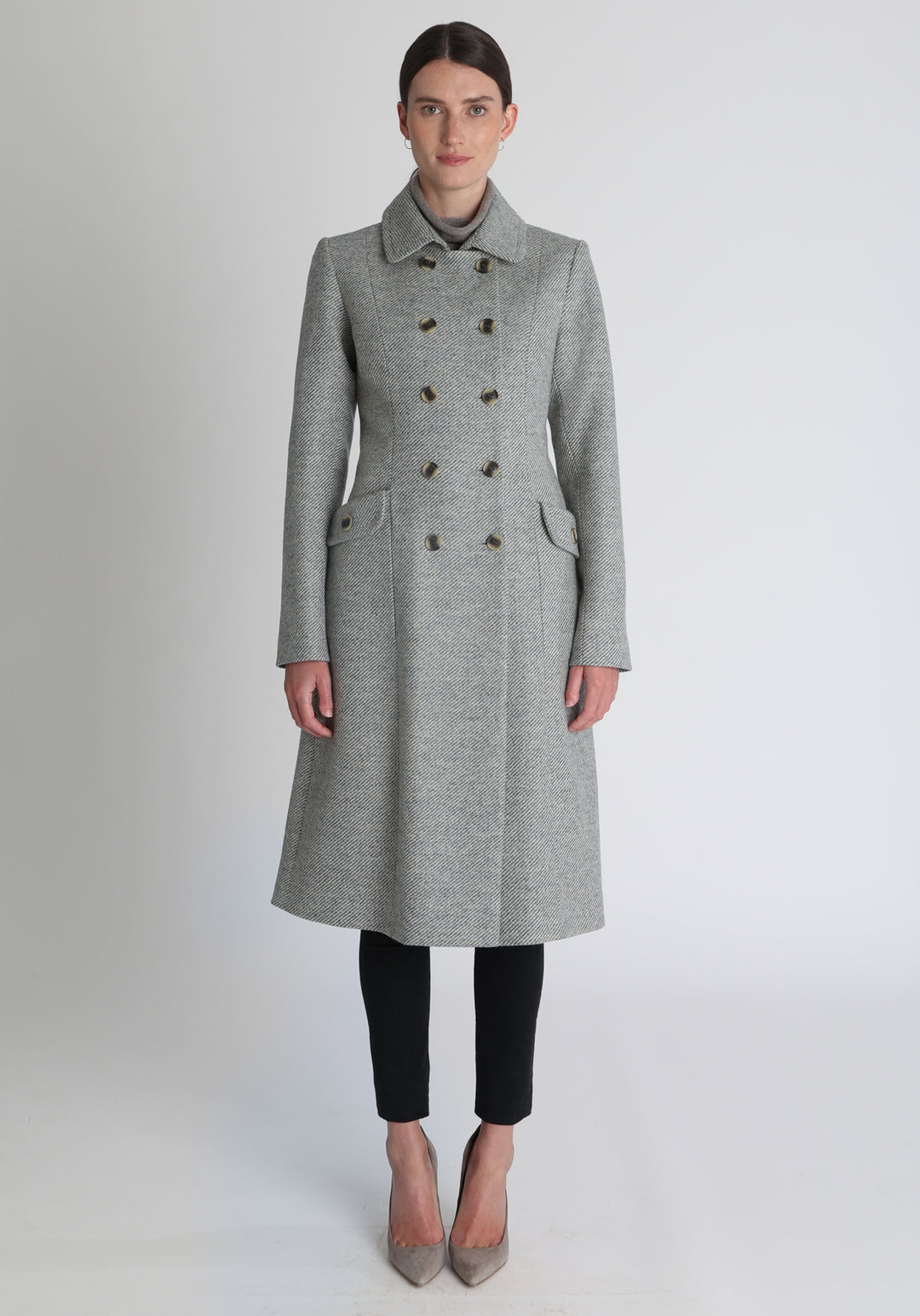 Model wearing the slate blue and cream lambswool twill, a vintage-inspired style with a double-breasted front, gently flared skirt, and curved detailing on the collar, pockets, and back belt.