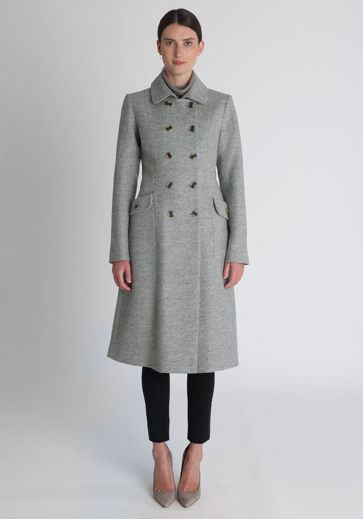Model wearing the slate blue and cream lambswool twill, a vintage-inspired style with a double-breasted front, gently flared skirt, and curved detailing on the collar, pockets, and back belt.