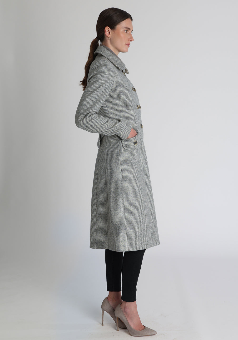Model wearing the slate blue and cream lambswool twill, a vintage-inspired style with a double-breasted front, gently flared skirt, and curved detailing on the collar, pockets, and back belt.