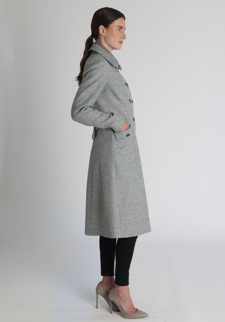 Model wearing the slate blue and cream lambswool twill, a vintage-inspired style with a double-breasted front, gently flared skirt, and curved detailing on the collar, pockets, and back belt.