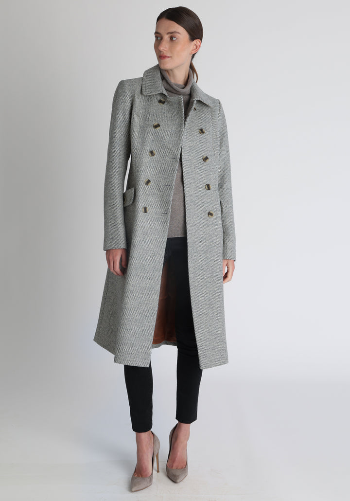 Model wearing the slate blue and cream lambswool twill, a vintage-inspired style with a double-breasted front, gently flared skirt, and curved detailing on the collar, pockets, and back belt.