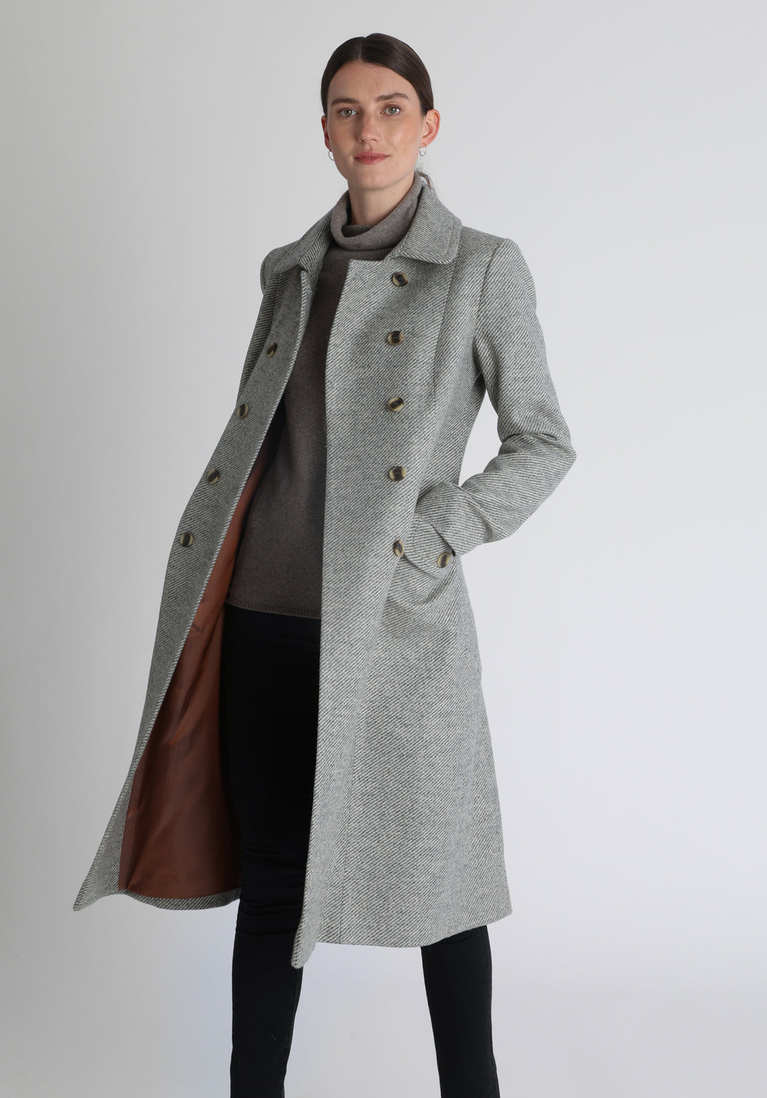 Model wearing the slate blue and cream lambswool twill, a vintage-inspired style with a double-breasted front, gently flared skirt, and curved detailing on the collar, pockets, and back belt.