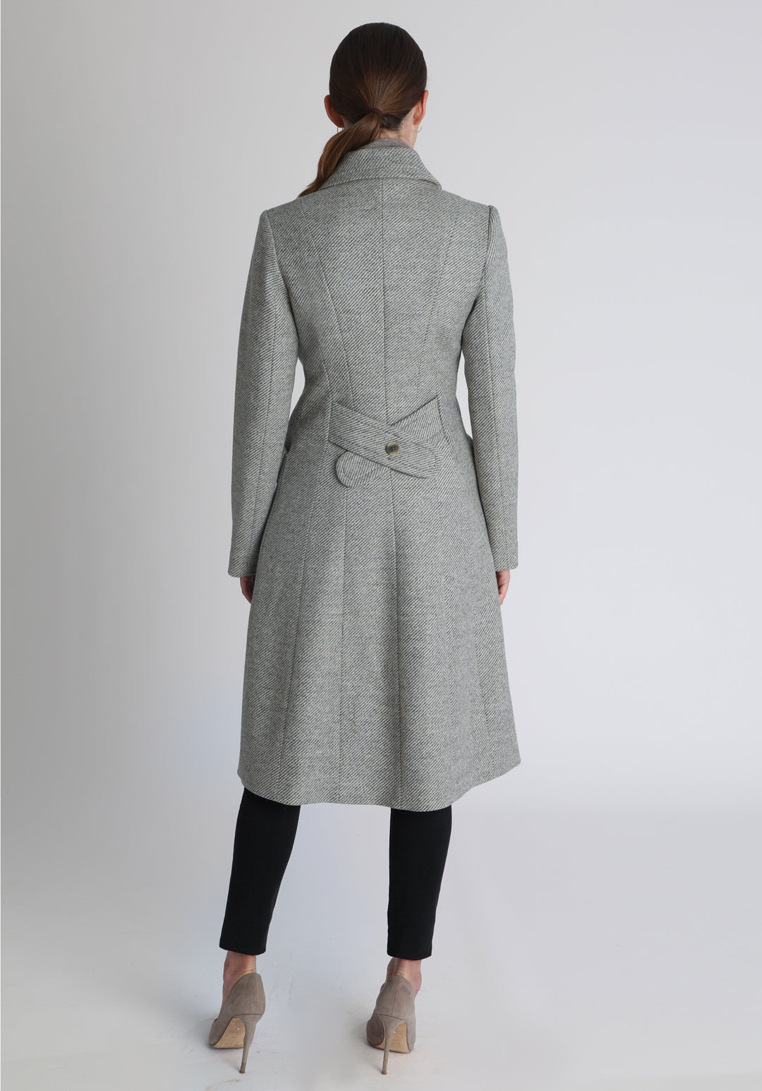 Model wearing the slate blue and cream lambswool twill, a vintage-inspired style with a double-breasted front, gently flared skirt, and curved detailing on the collar, pockets, and back belt.