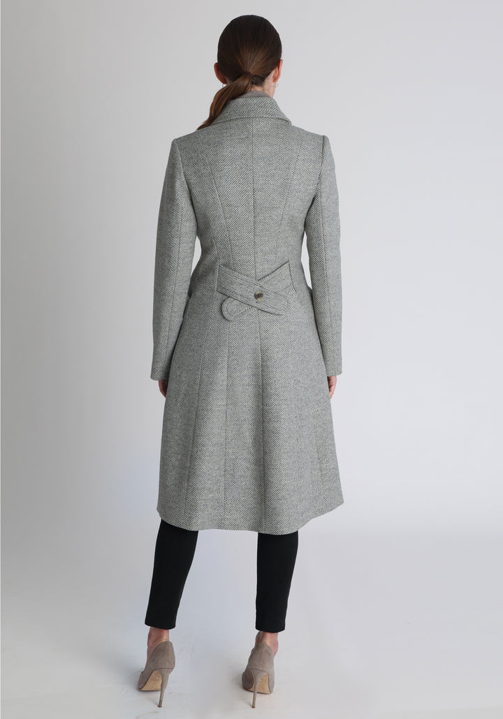 Model wearing the slate blue and cream lambswool twill, a vintage-inspired style with a double-breasted front, gently flared skirt, and curved detailing on the collar, pockets, and back belt.