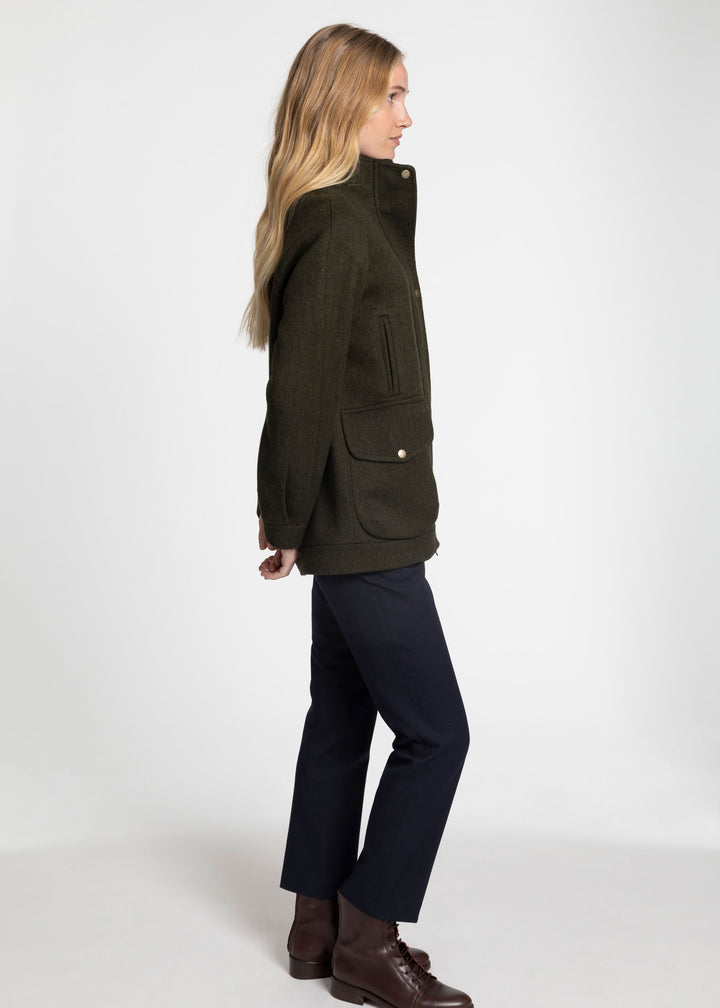 A side view of a woman wearing a dark green wool jacket.