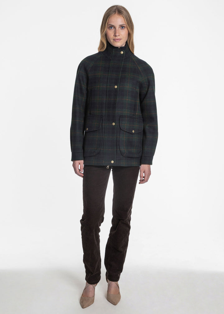 A woman wearing a navy and green plaid jacket with metal snap buttons.