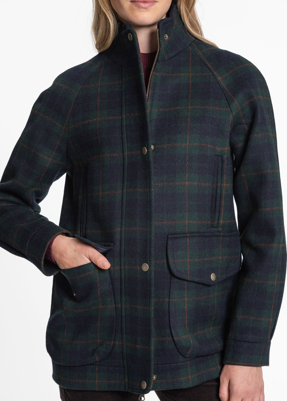 A woman wearing a dark green and navy plaid wool jacket with a high stand collar, snap-button front, and flap pockets, shown against a plain white background.