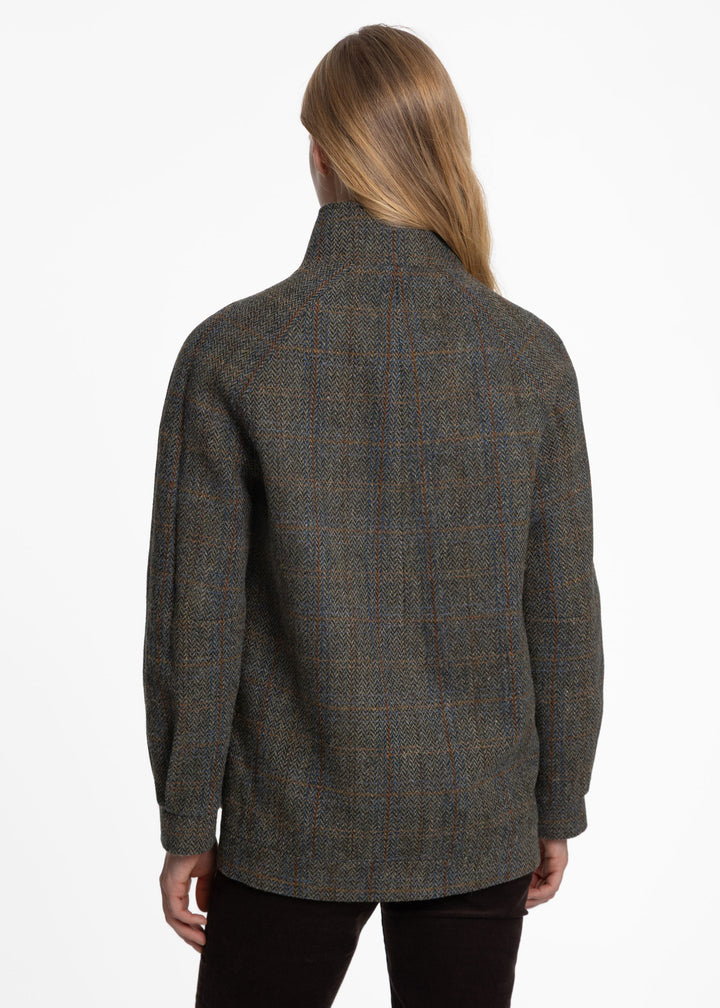Back of a woman wearing a textured green tweed jacket.
