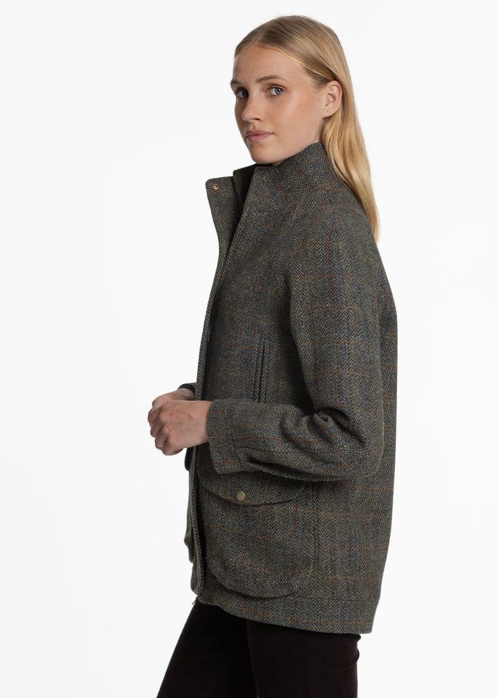 A woman wearing a textured tweed jacket in a side profile view against a plain white background.