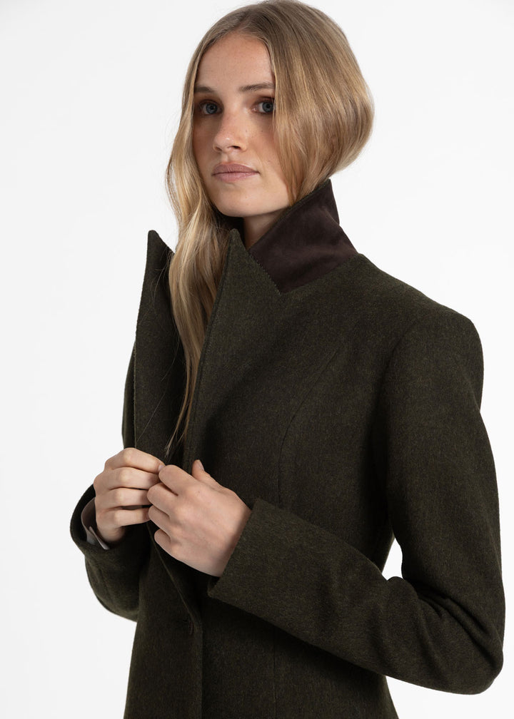 Close up of a woman wearing a dark olive green wool coat. The collared is turned up, highlighting a suede brown under collar detail.