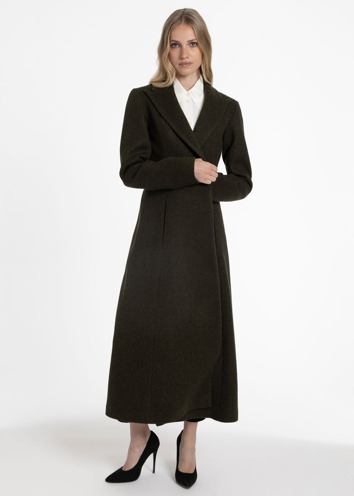 Woman wearing a dark olive green wool coat with a white collared shirt.