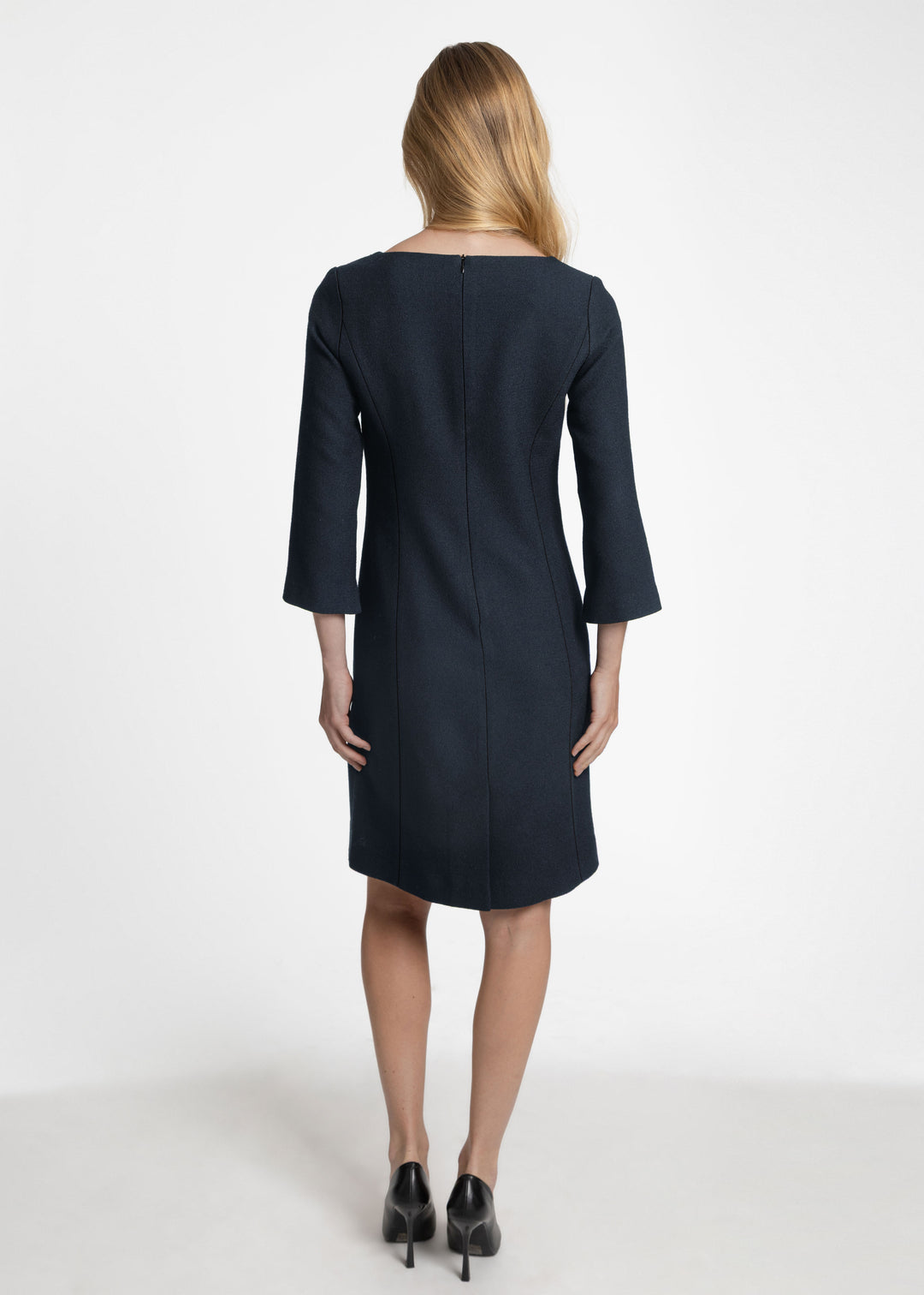 Back view of a woman modeling a dark navy knee length dress with three-quarter length sleeves.
