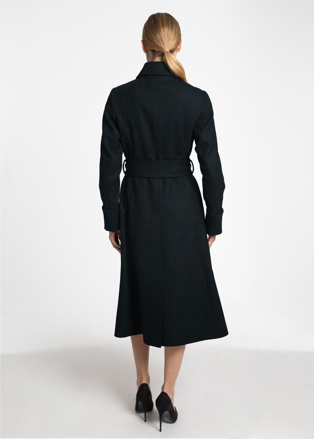 A back view of a woman wearing a dark green wool belted coat.