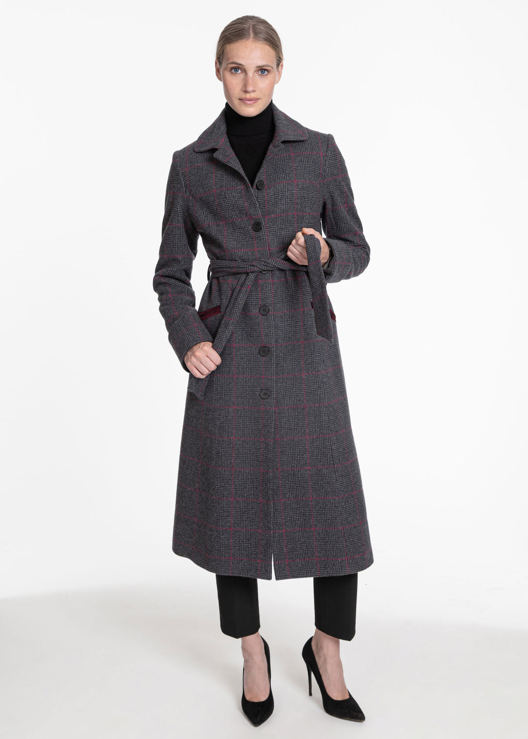 A woman wearing a black and grey plaid belted wool coat with pink overcheck and mulberry velvet detailing.
