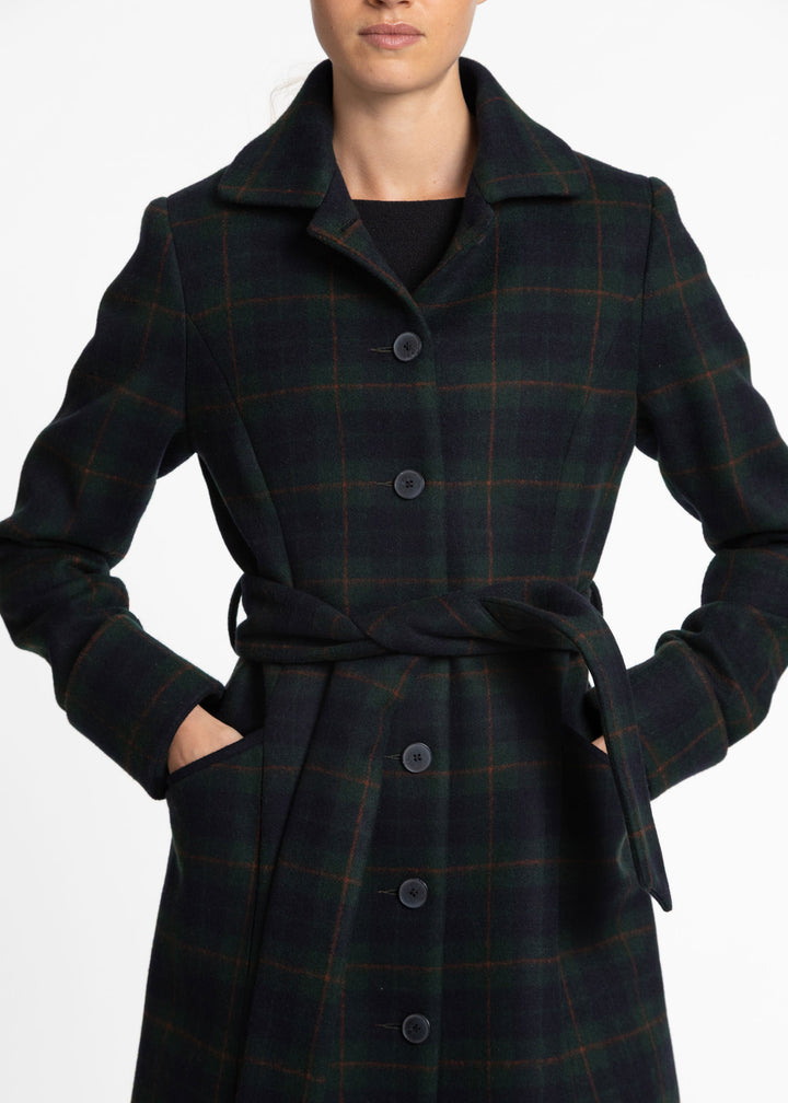 Close up of a woman wearing a navy and dark green plaid wool coat with buttons and a belted closure.