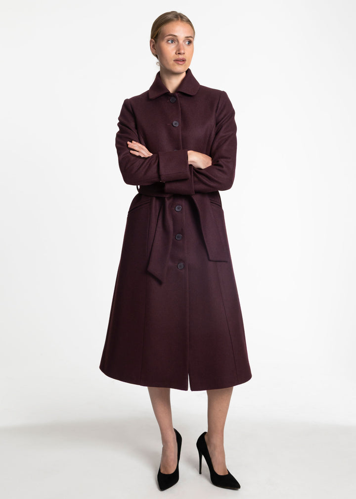 A woman wearing a belted wool coal in mulberry.
