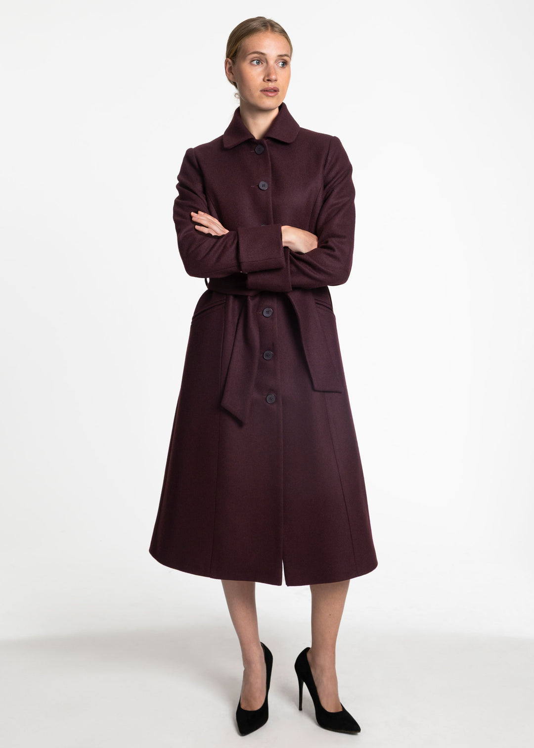 A woman wearing a belted wool coal in mulberry.