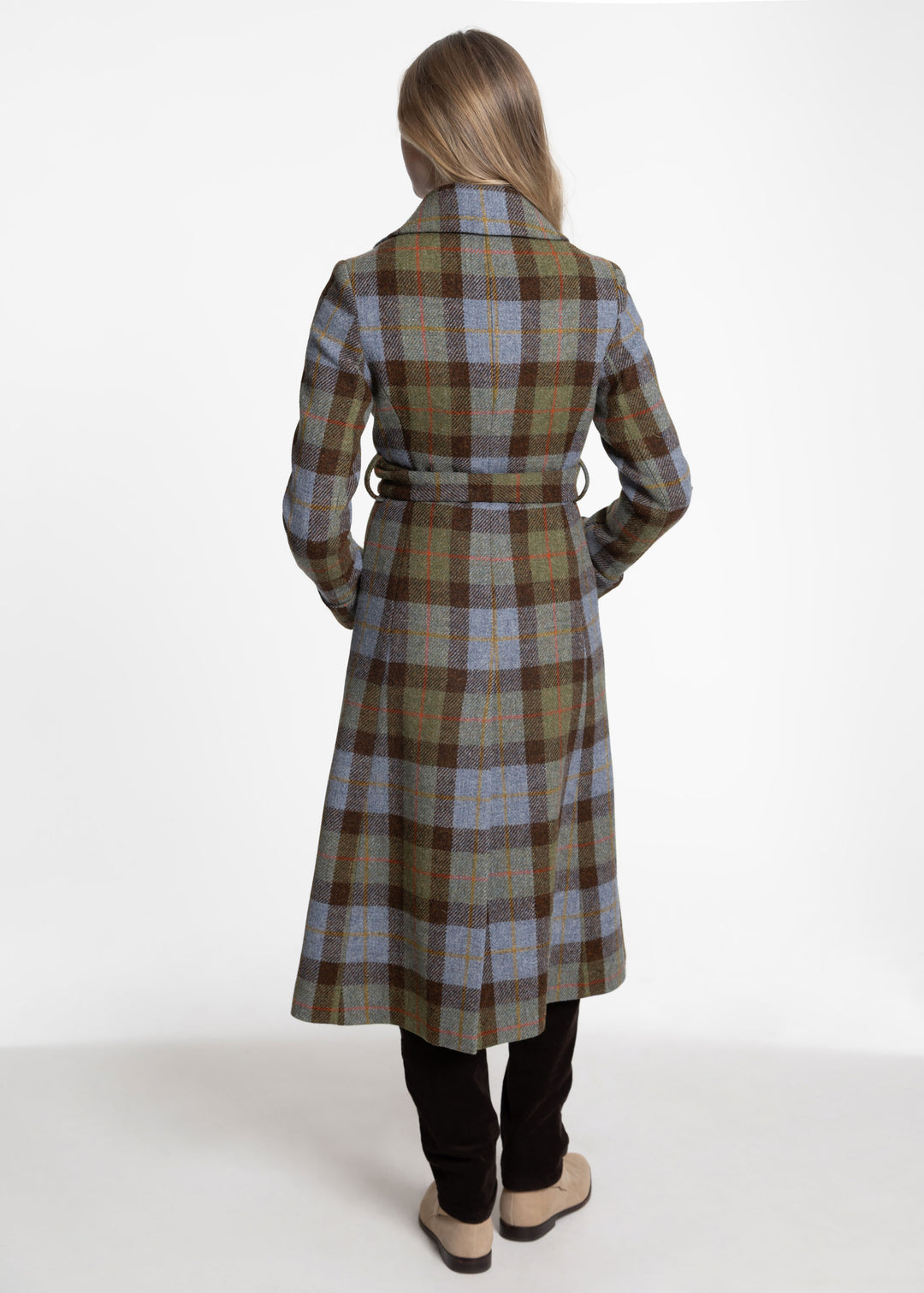 Back view of a woman modeling a brown, blue and green plaid coat with a belt closure.