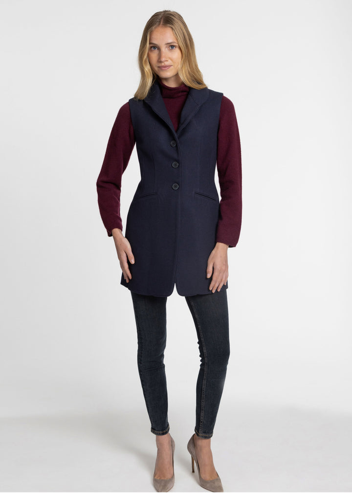 Women wearing a navy wool sleeveless waistcoat with a maroon sweater underneath.