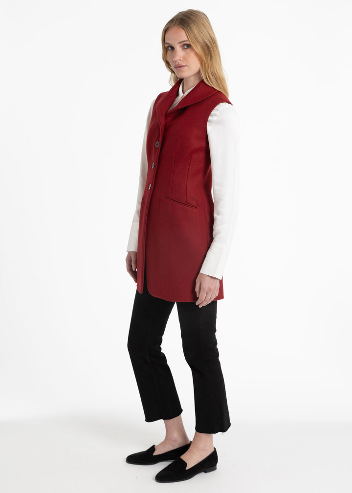Side view of a woman wearing a red wool waistcoat with a white collared shirt underneath.