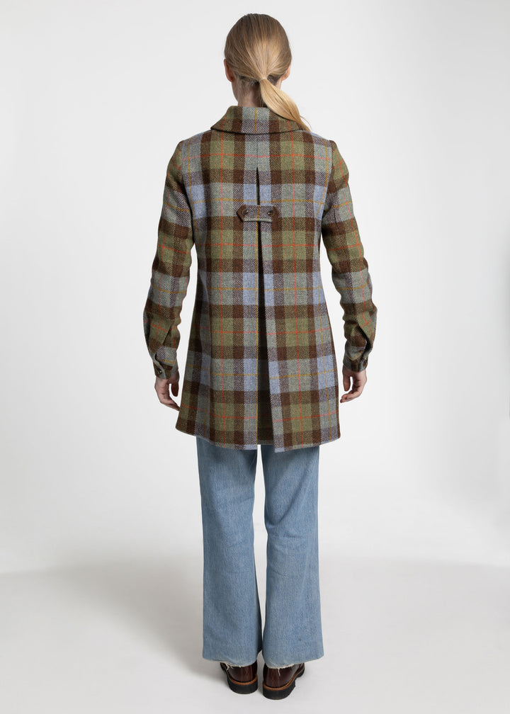 Back view of a woman wearing a brown, blue and green plaid coat with a pleat detail.