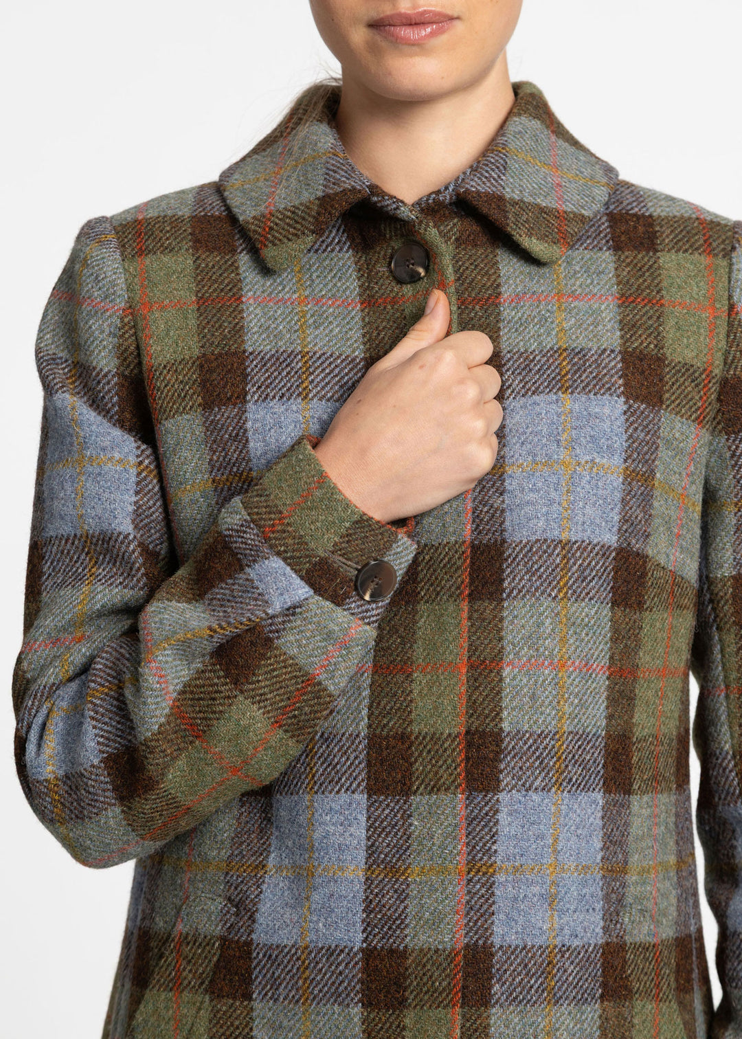 A close up of a woman wearing a brown, blue and green plaid coat with red and yellow overcheck. 