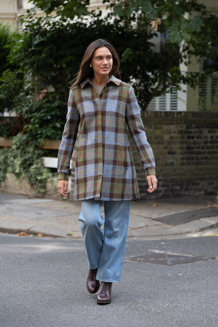 Woman wearing a blue, brown, and green plaid coat paired with blue jeans.
