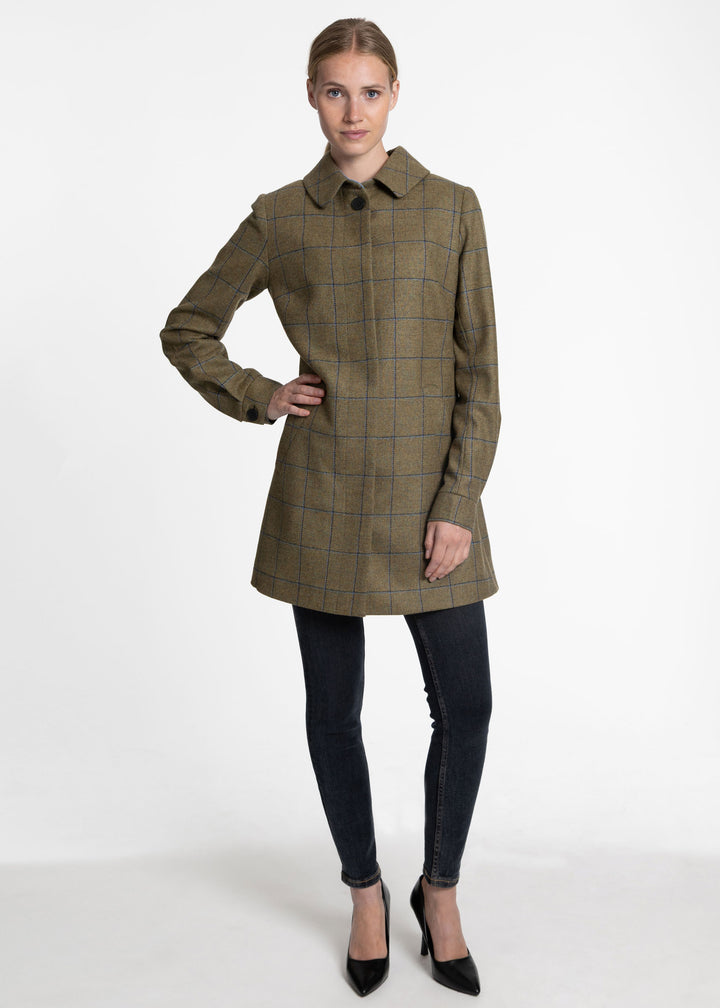 Woman wearing a green wool coat with black and blue windowpane check.