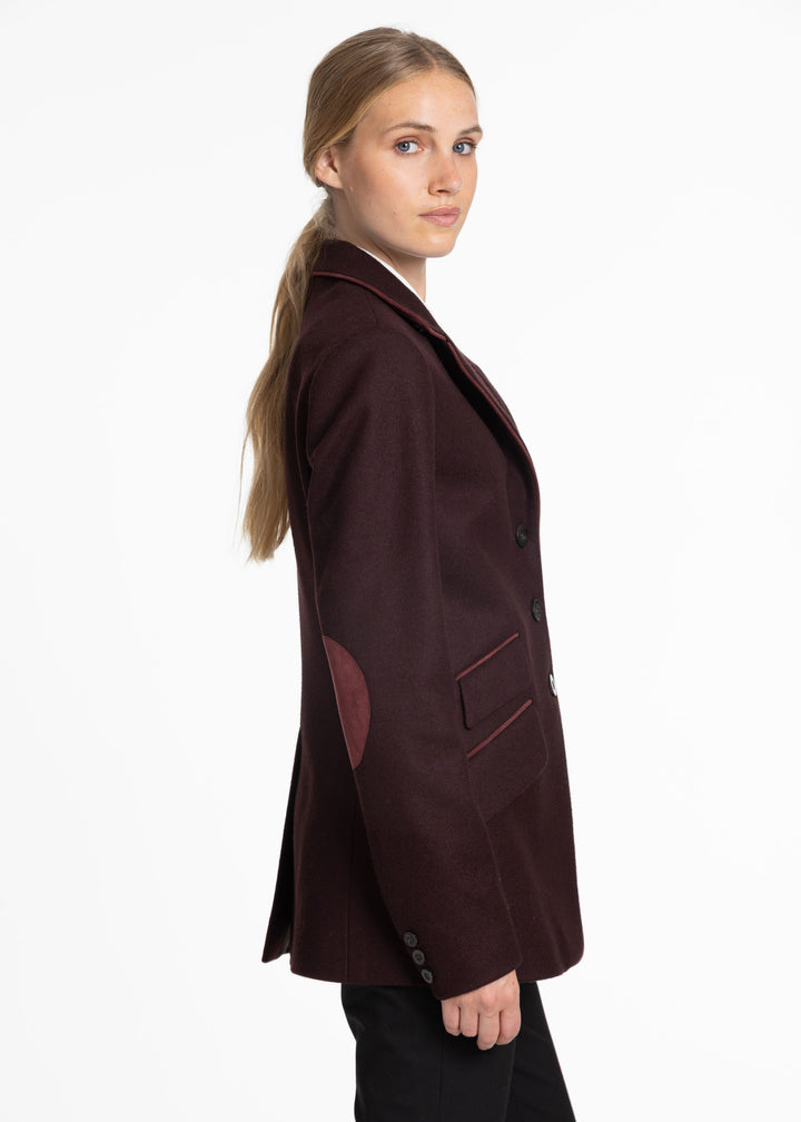 Side profile of a woman wearing a mulberry jacket with burgundy trim and burgundy suede elbow patches.