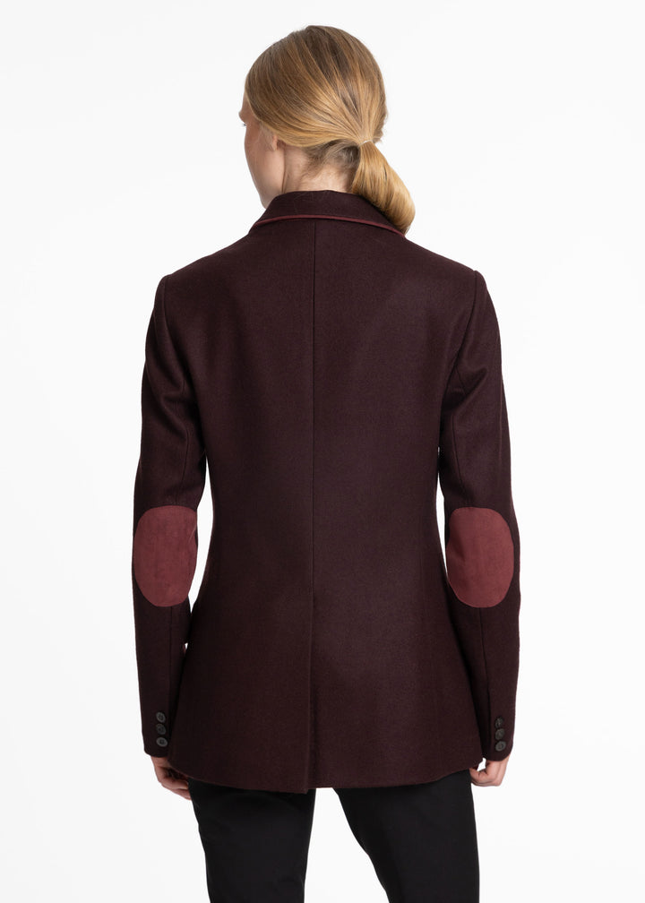 Back view of a woman wearing a mulberry wool jacket with burgundy trim and burgundy elbow patches.