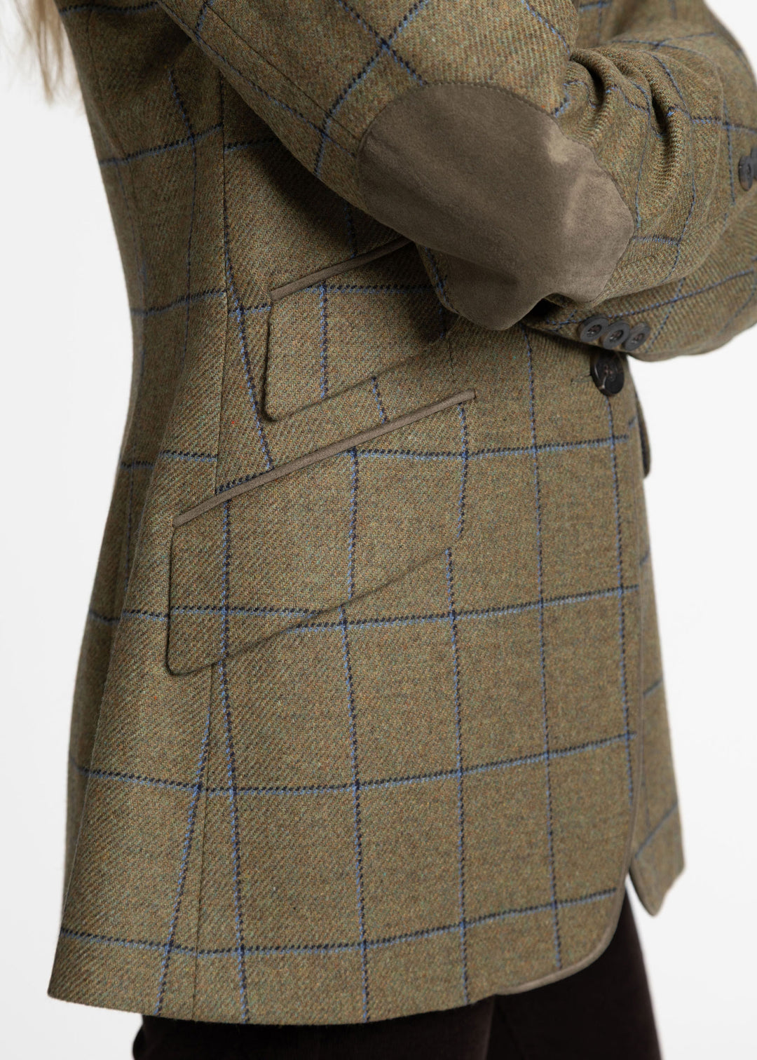 Close-up of a green tweed jacket with blue windowpane check lines, and solid green suede elbow patches.