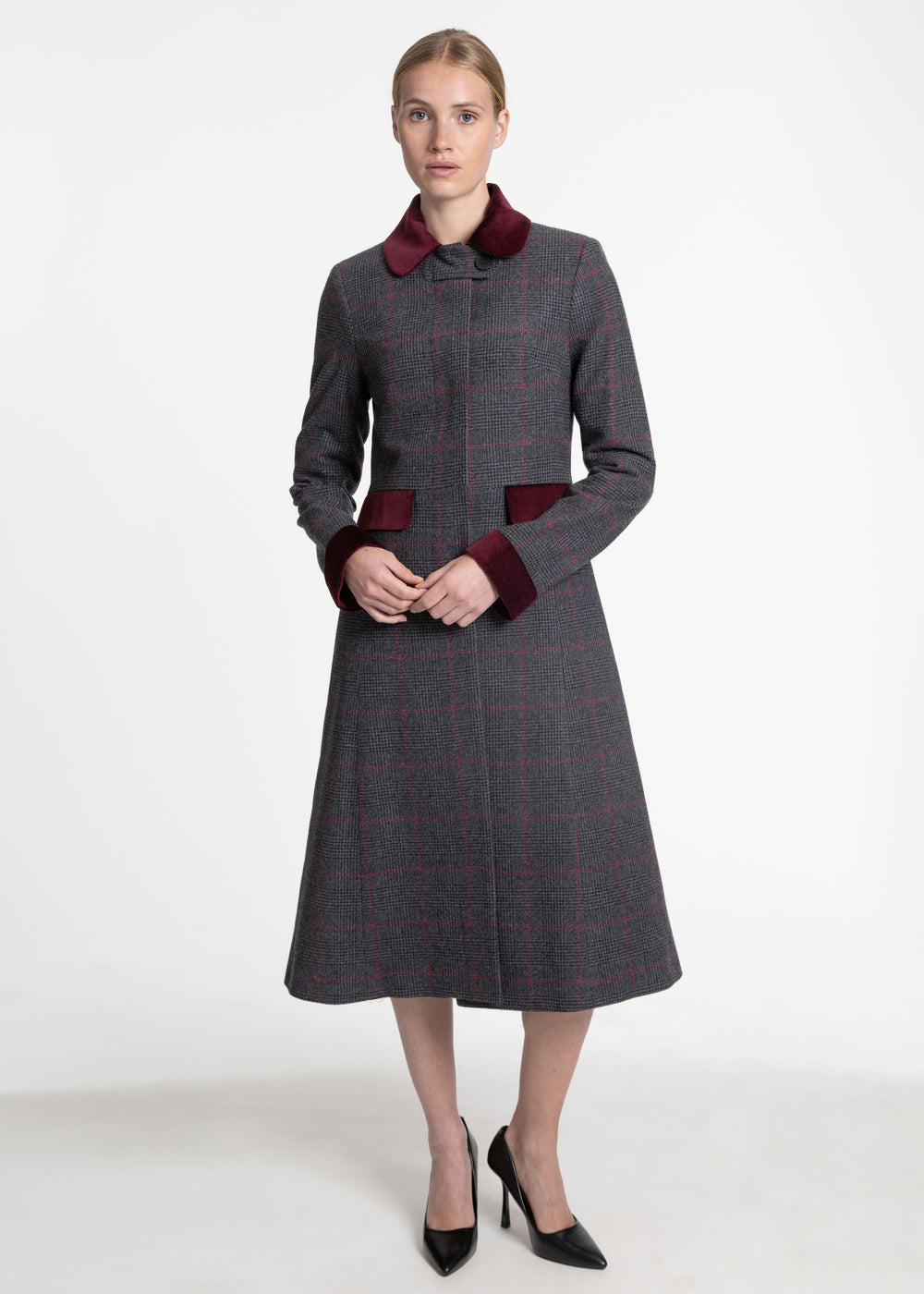 A woman wearing a black and grey plaid check coat with pink accents and burgundy velvet collar, cuffs and pocket flaps.