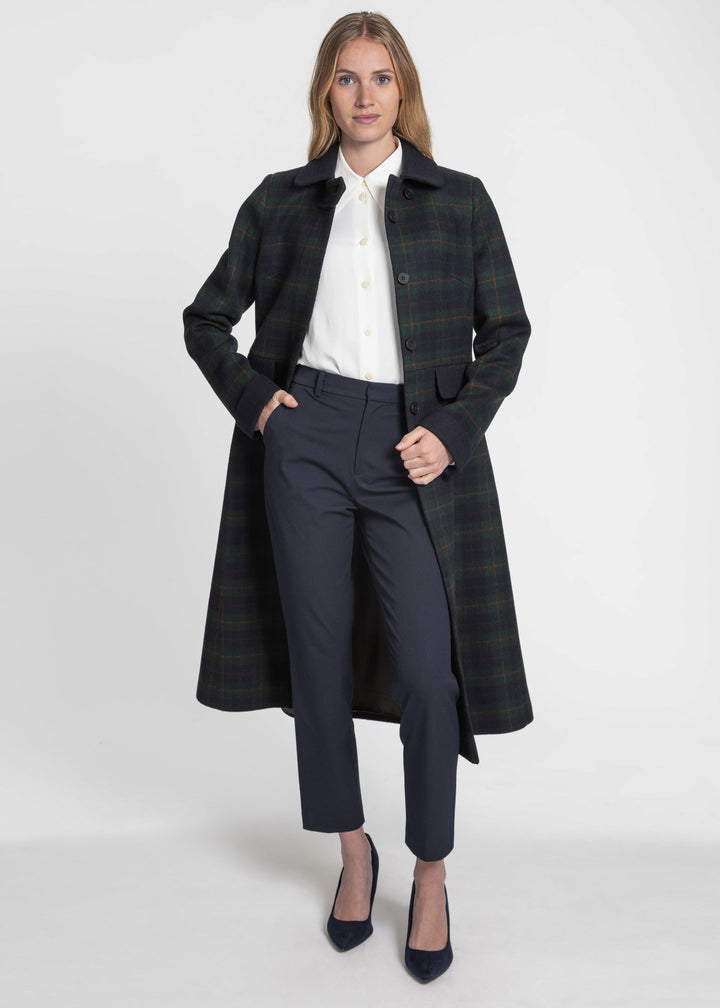 Woman styling a navy and green check coat styled with navy trousers and a white collared shirt.