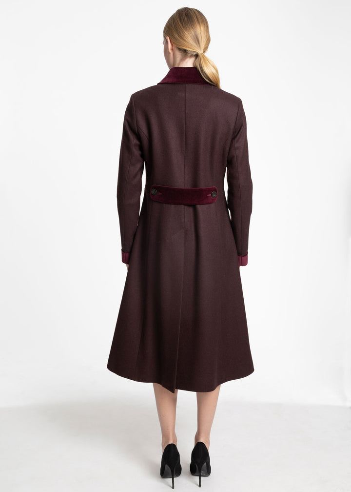 Back view of a woman wearing a mulberry coat with burgundy velvet contrast on the back belt, collar, and cuffs.