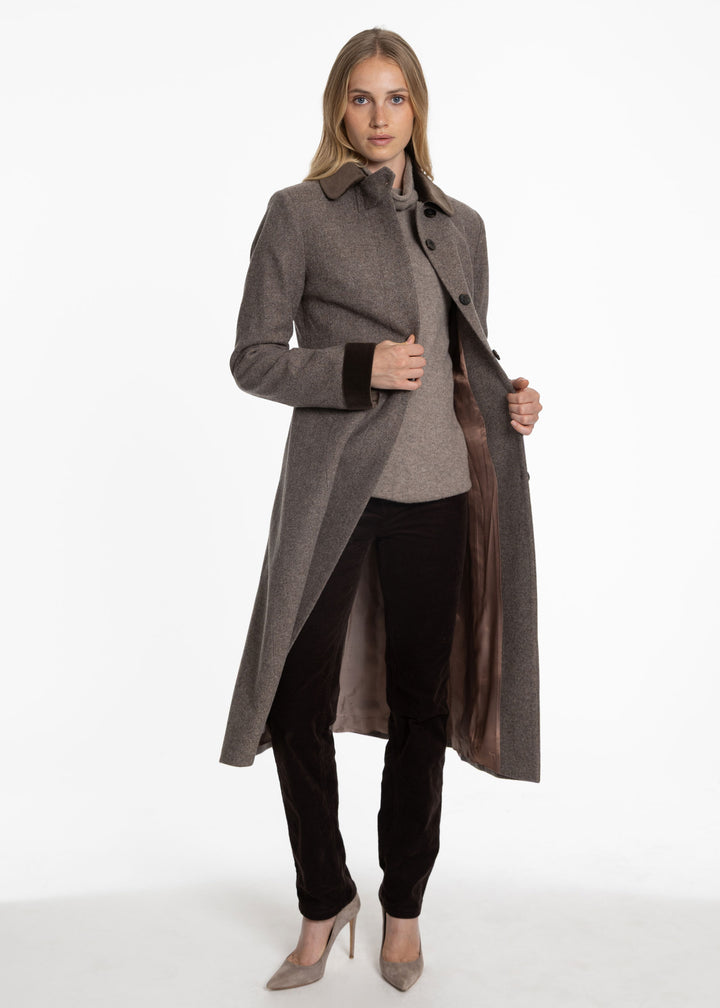 Woman wearing a purple-brown coat with brown velvet accents and a blush lining. 