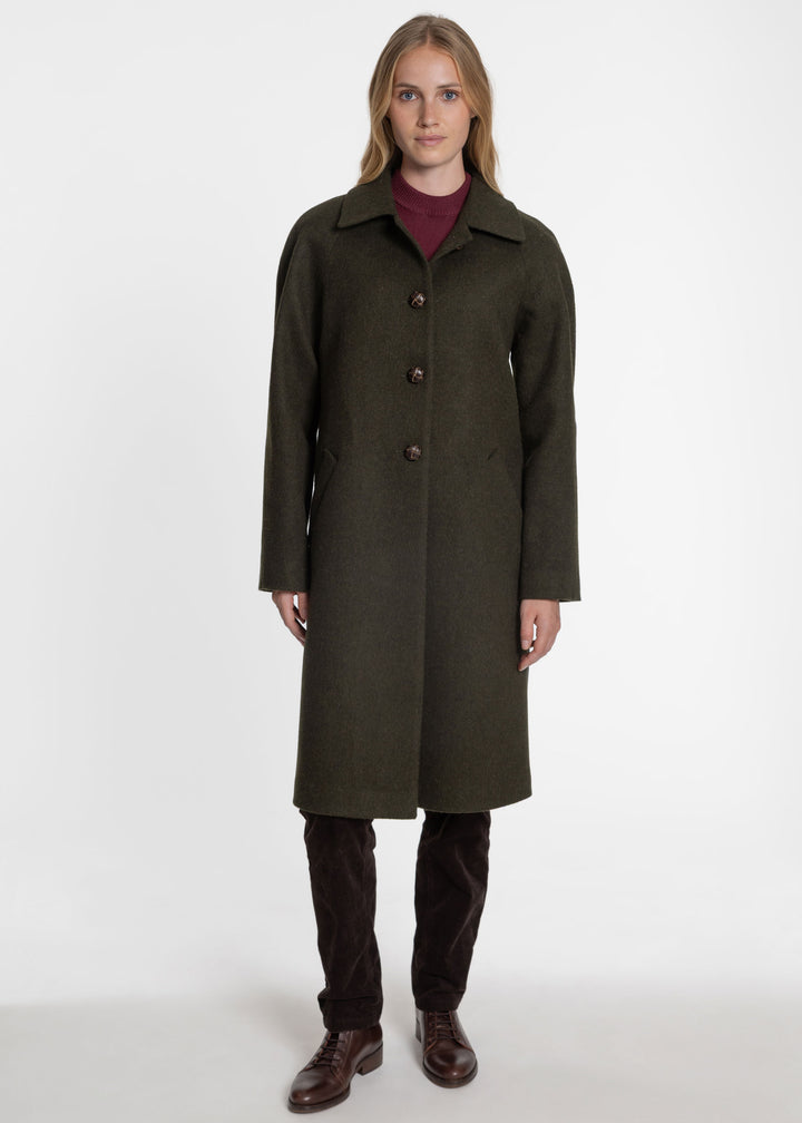 Woman wearing a dark green wool coat with brown buttons.