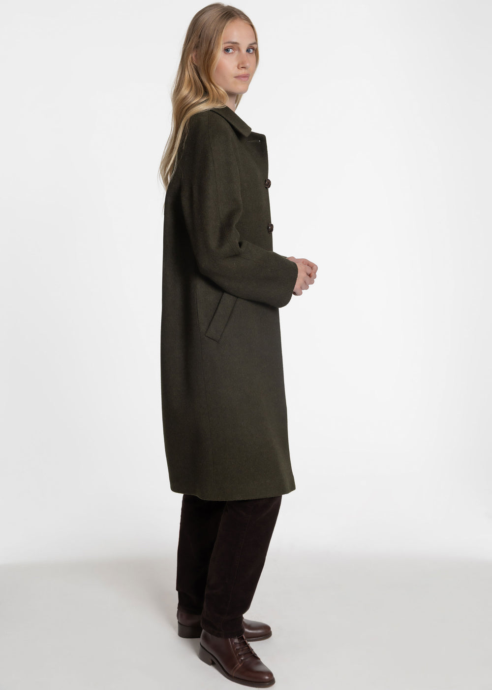 Side view of a woman wearing a dark green wool coat.